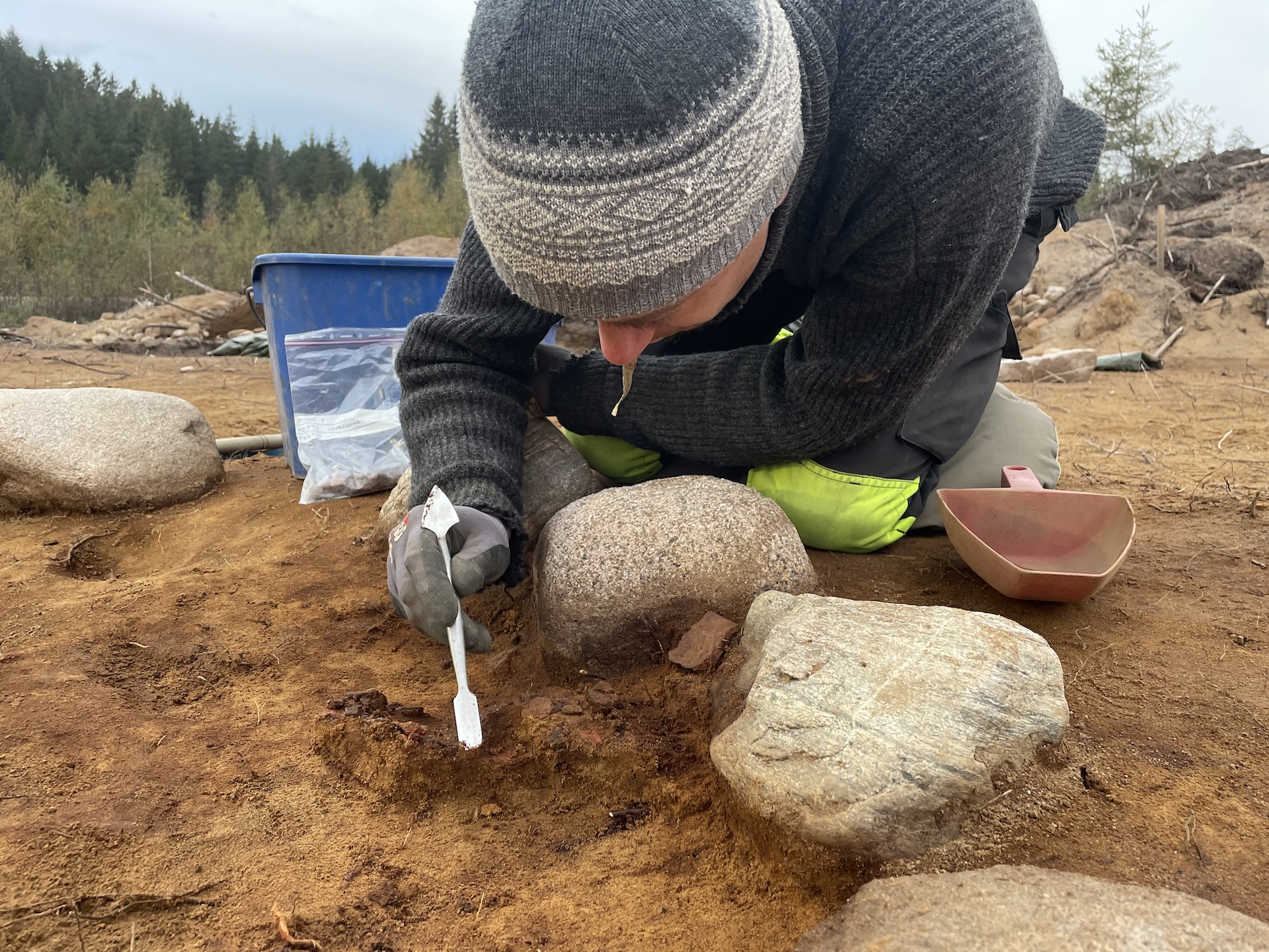 A close-up of a man excavating the graves with a small tool