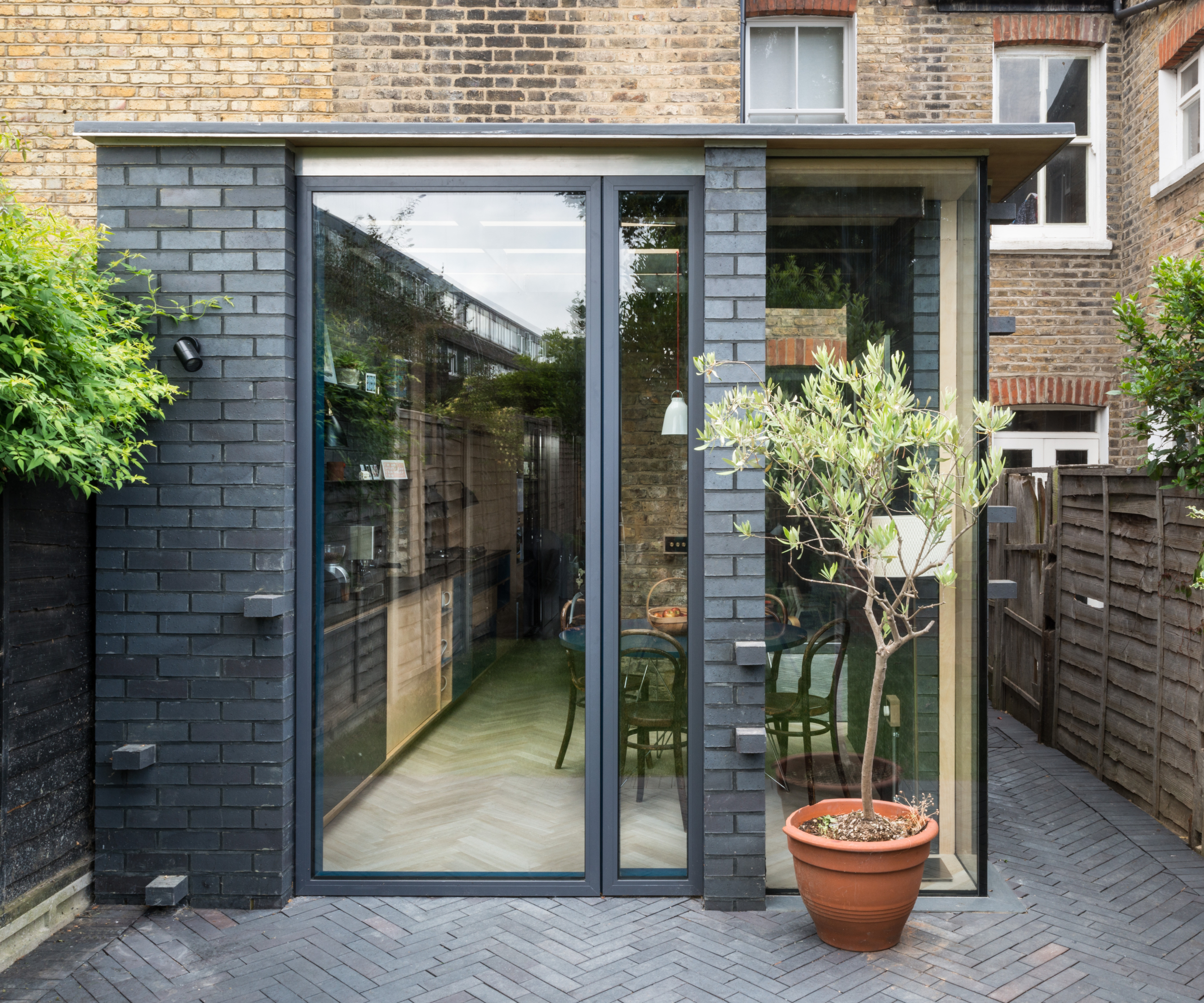 outside of small house extension with blue brick walls and kitchen inside