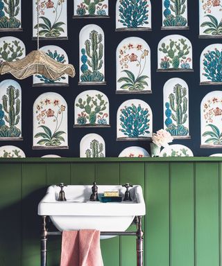 Cloakroom with wood panelling, tongue and groove painted green, with a basin and botanical pattern wallpaper.