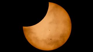 The shadow of the moon passes partly over the orange sun during the Oct. 14 solar eclipse