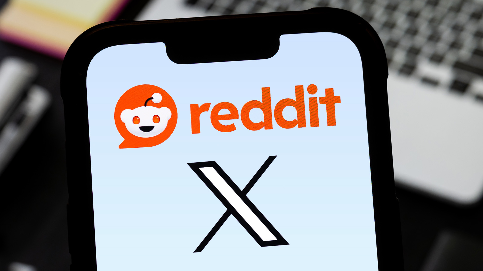 Reddit and X logos on a phone