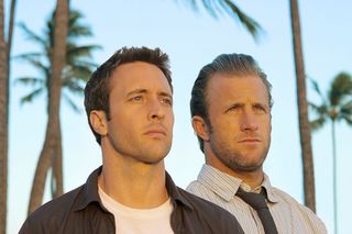 two stars of the Hawaii Five-0 reboot standing in front of palm trees