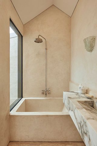 a tadelakt bathroom with a built in bath