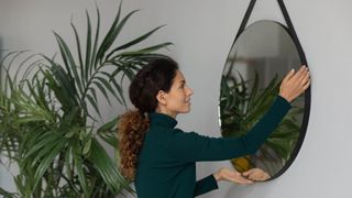 Woman putting up wall mirror