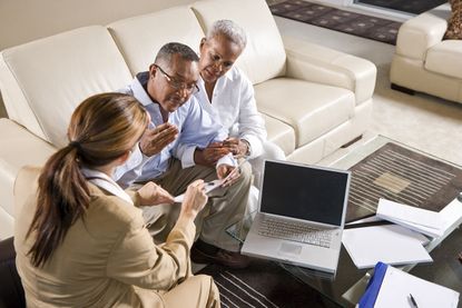 Senior African American couple meeting with female financial adviser reviewing report