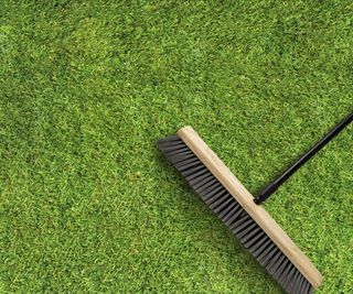 A broom resting on some fake grass