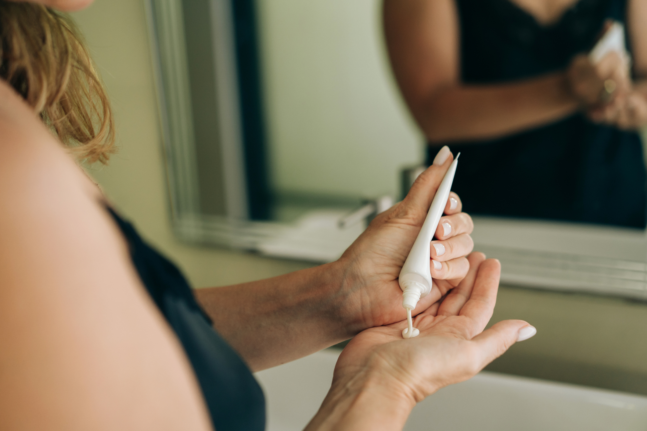 A woman pours out moisturizer to apply.
