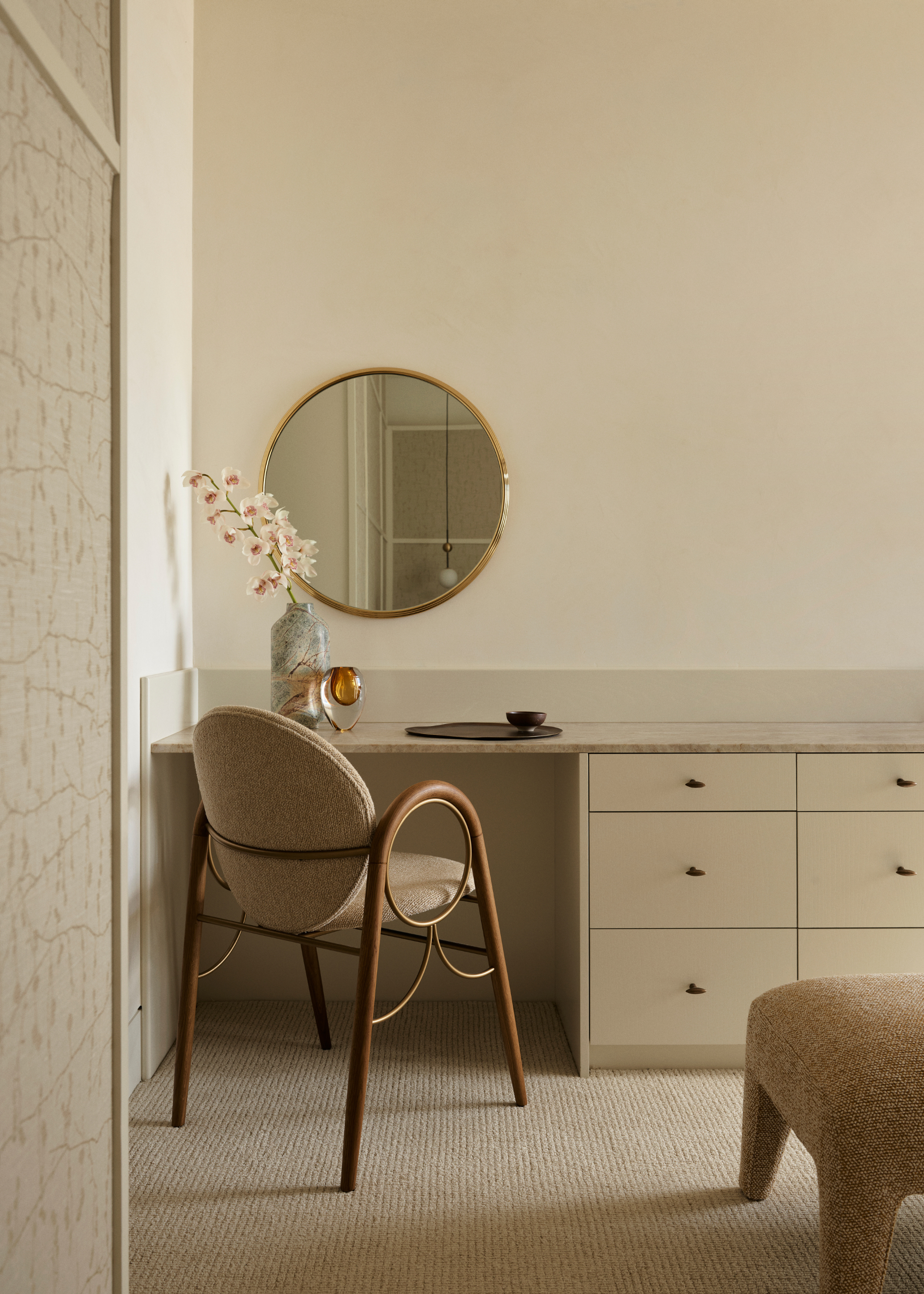 A bedroom with a dresser drawer near a vanity with a mirror and a chair