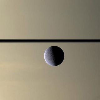 The Cassini spacecraft looks toward the Rhea's cratered, icy landscape with the dark line of Saturn's ringplane and the planet's murky atmosphere as a background. Rhea is Saturn's second-largest moon, at 1,528 kilometers (949 miles) across. This image was