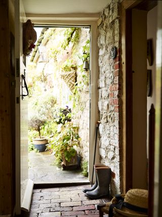 front door opening into garden from brick hallway