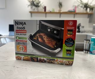 The Ninja Foodi FlexBasket Air Fryer in a box on a kitchen counter.