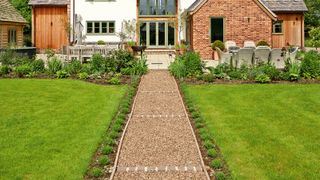 The lawn at the front of a house with a straight gravel path running through the middle