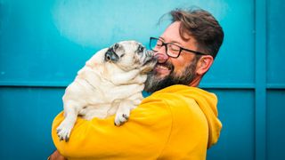 Pug giving a happy-looking man a kiss