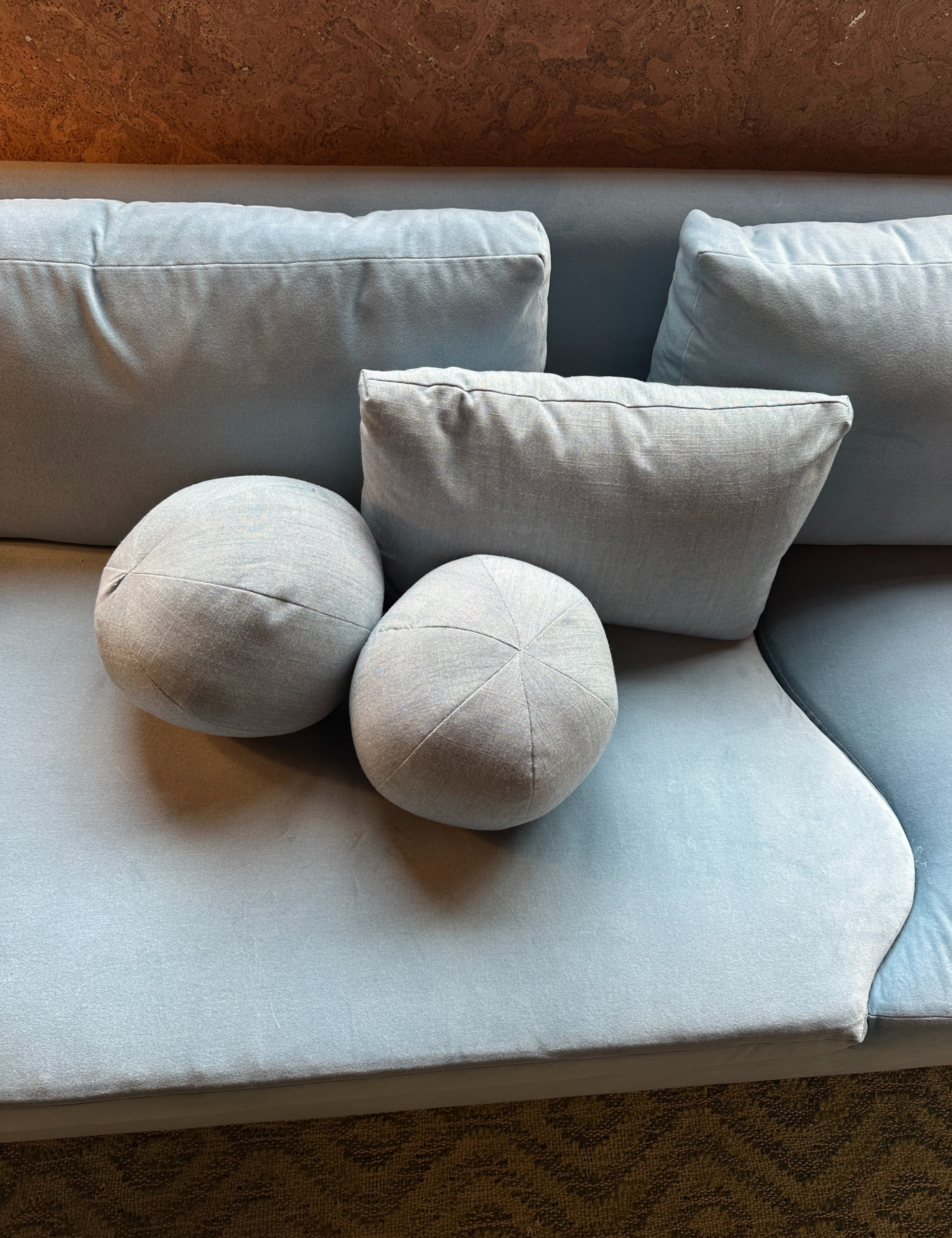 Sky blue 'ball pillow duo styled atop of a sofa with matching upholstery
