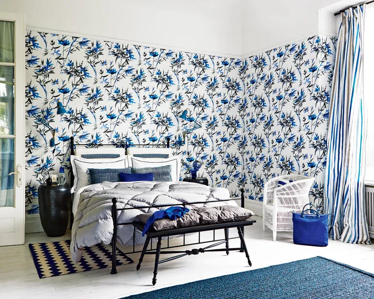 A bedroom with black, white and blue patterned wallpaper