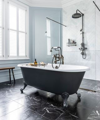 White tiled bathroom with freestanding matte graphite gray bathtub and walk in shower with chevron tiling