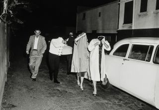 A bevy of hookers cover up after a vice squad raid at the Carolina Pines Restaurant on Melrose Avenue, c1957