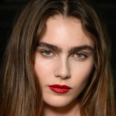 A model wearing red lip liner and lipstick.