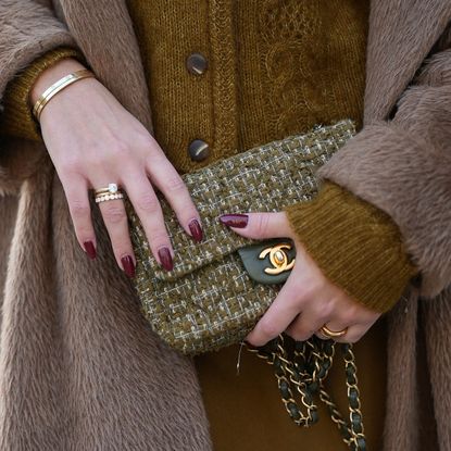 best nail shades for party season Laura Noltemeyer is seen wearing a a long camel-colored brushed wool coat with a wrap silhouette and integrated belt by Max Mara; a mustard-colored knit cardigan with a brushed cable-knit pattern and front button fastening by Sézane; a mustard yellow brownish mini skirt in a soft wool fabric by Sézane; a small quilted tweed flap bag in a khaki Color with woven fabric material with a gold chain strap and CC clasp by Chanel; among her jewelry are a white gold „LOVE“ ring and a „Trinity“ ring by Cartier; a white gold „LOVE“ bracelet by Cartier; gold diamond rings by Ariane Ernst on November 13, 2025 in Hamburg, Germany