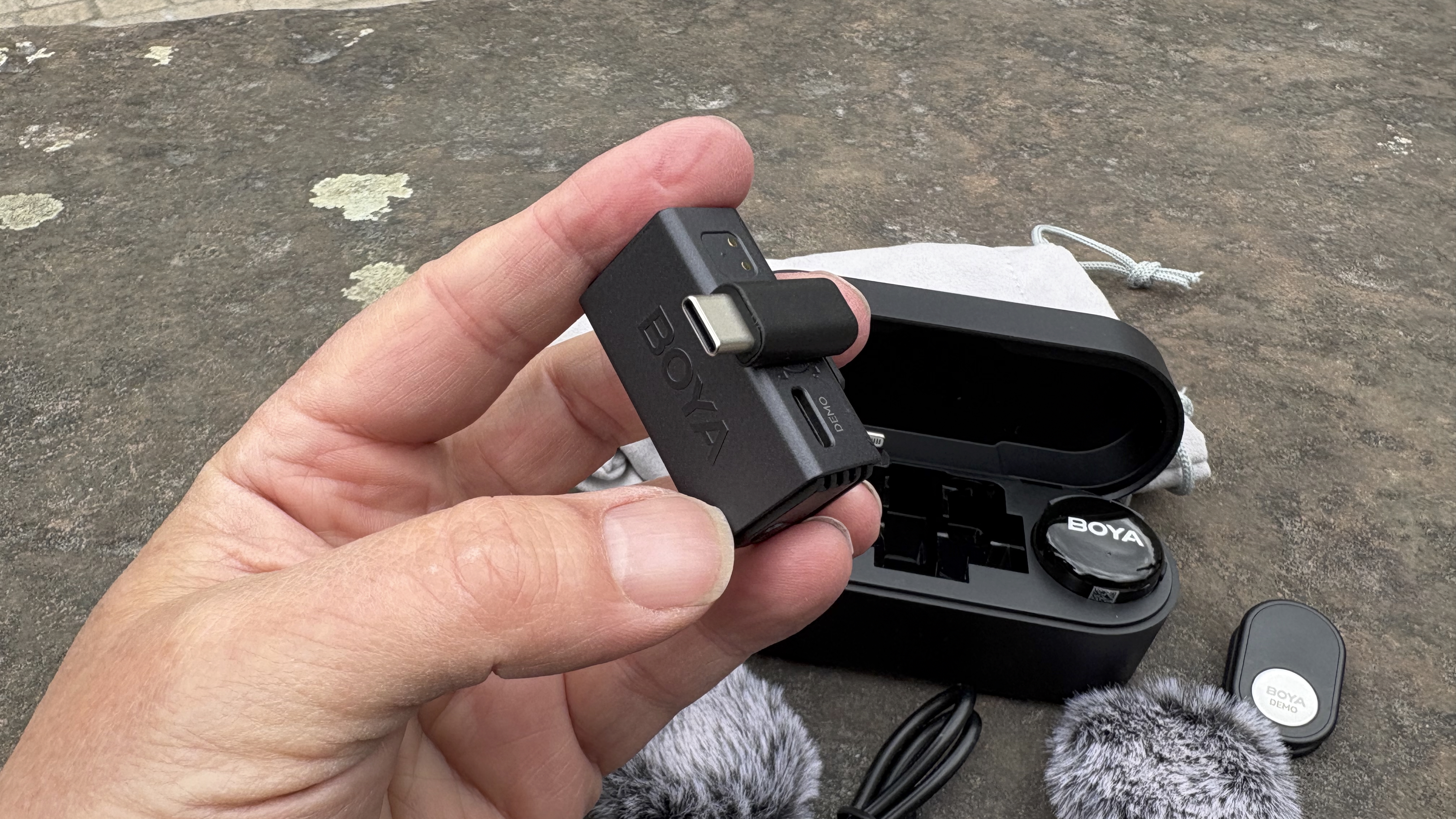 Close-up of a hand holding the receiver up to the camera. The USB-C adaptor is attached to the receiver
