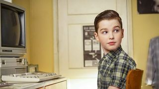 A young Sheldon Cooper looks behind him as he sits at a computer in Young Sheldon