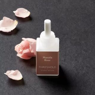 A small Pura fragrance bottle surrounded by rose petals