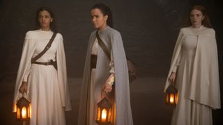 Egwene, Nynaeve, and Elayne stand in a dark room holding lanterns in The Wheel of Time season 2