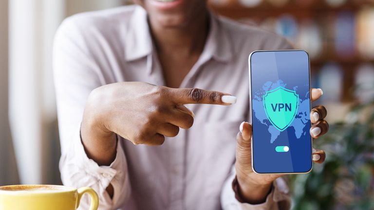 Woman holding smartphone up with VPN graphic on the screen and pointing at it