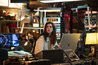 Solos: Physicist Leah, played by Anne Hathaway, sits in her lab wearing a white overshirt and surrounded by various computers and scientific devices, a look of alarm on her face