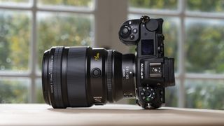 Nikon Z 135mm f/1.8 S Plena lens on a wooden table attached to Nikon Z6 II