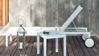 A white sun lounger with wheels on wooden decking