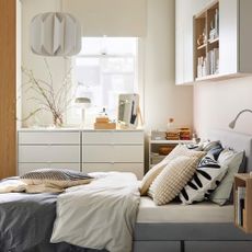 A bedroom with a grey upholstered bed and white walls