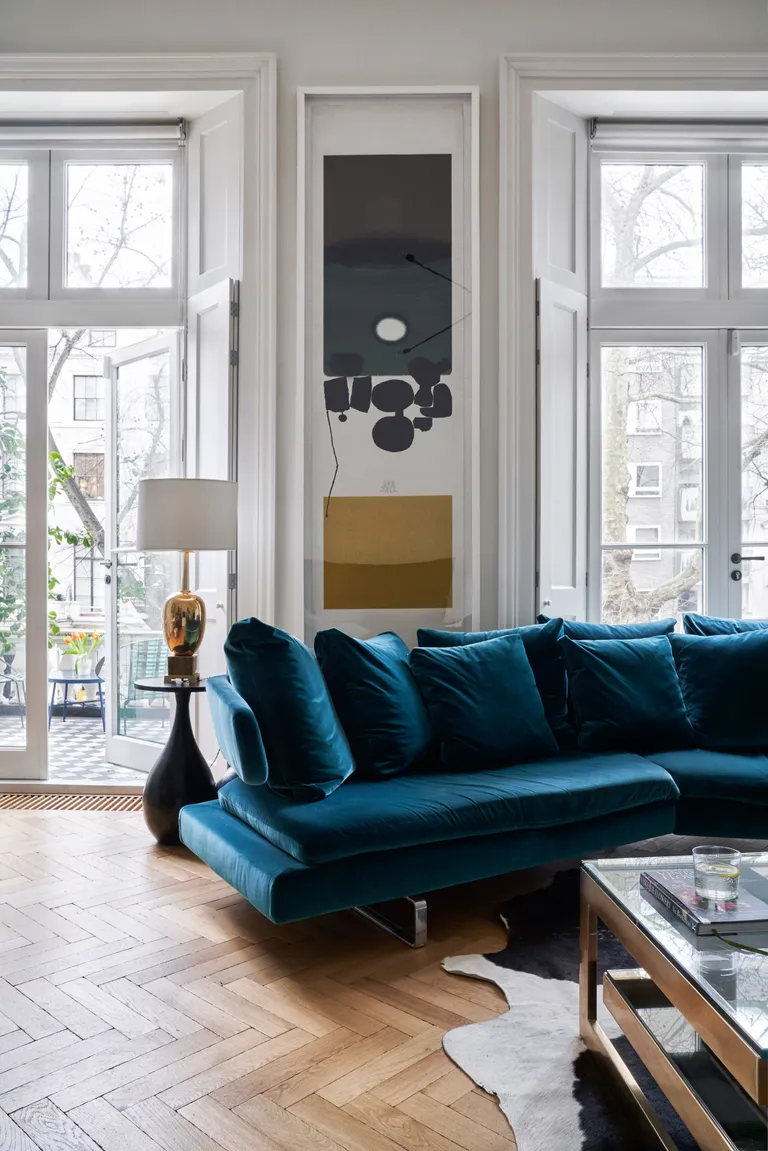 White living room with blue velvet sofa