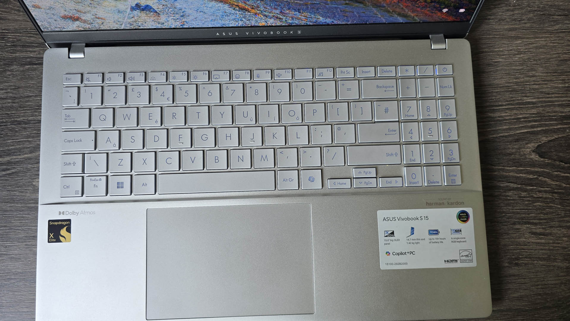 The Asus Vivobook S 15 Copilot+ in silver pictured on a wooden desk.