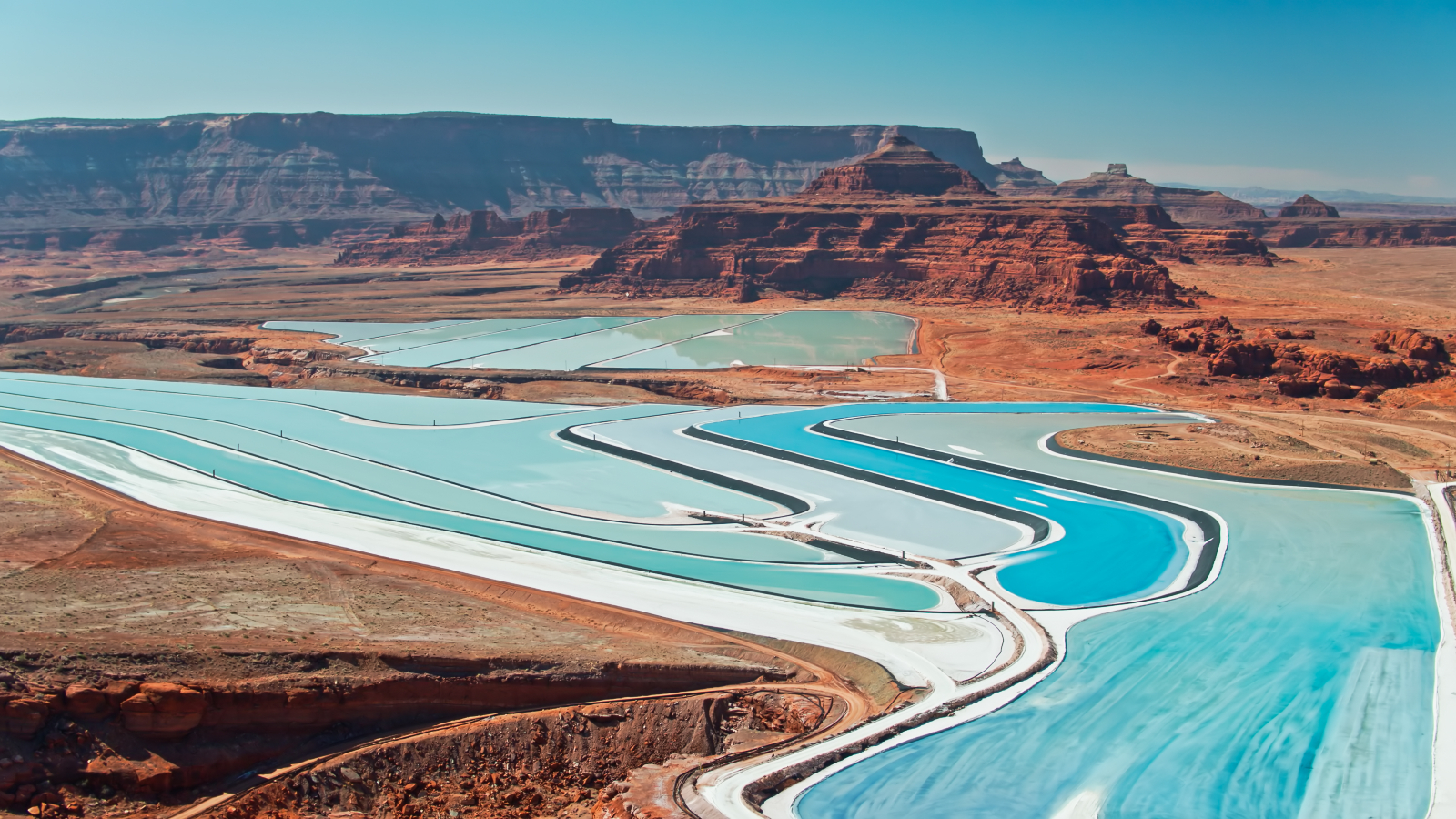 A ground-level photo of the potash ponds near Moab showing their blue waters contrasting with the rusty orange hues of the Colorado Plateau
