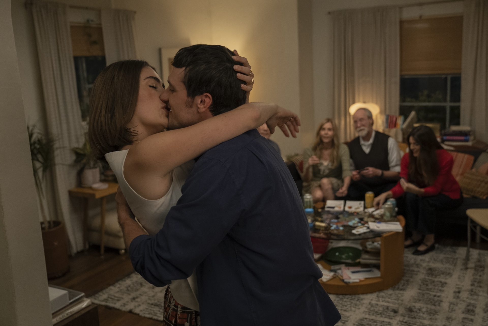 rachel sennott as maia kissing her boyfriend dylan in their living room while guests play a board game in a scene from i love la season 1