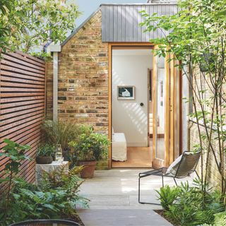 Courtyard patio garden with a fence on one side and a metal chair on the other