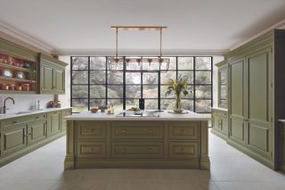 Large kitchen looking out onto a garden with wooden island and green cabinets