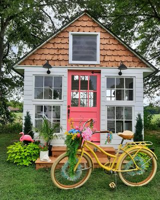 She shed in the backyard with red colored front door and yellow bike