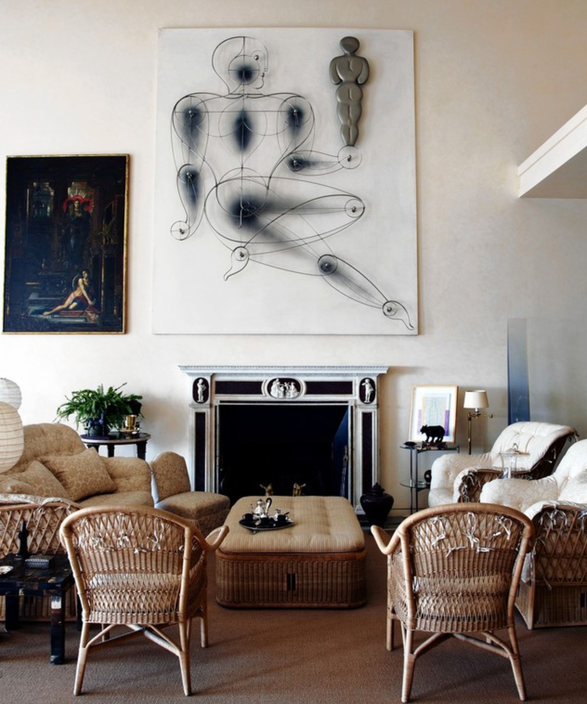 Living space with high ceilings, large artwork above fireplace, mixture of seating surround with ottoman in middle