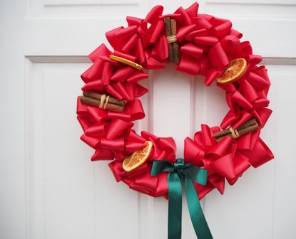 red ribbon wreath with Christmas dried fruit and green bow on a white door