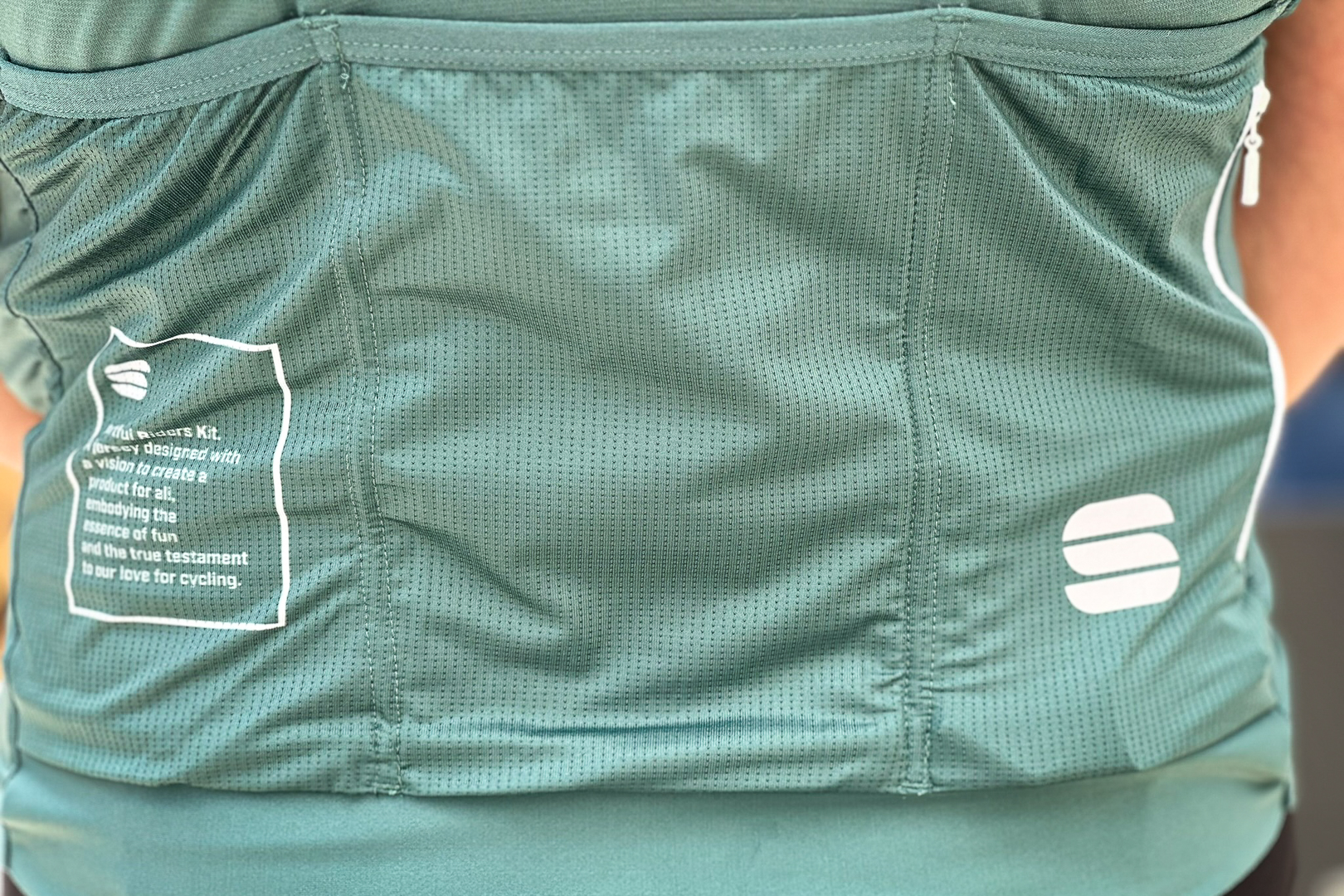 Close up of a green jersey with three rear pockets with Lycra edging and a zipped security pocket