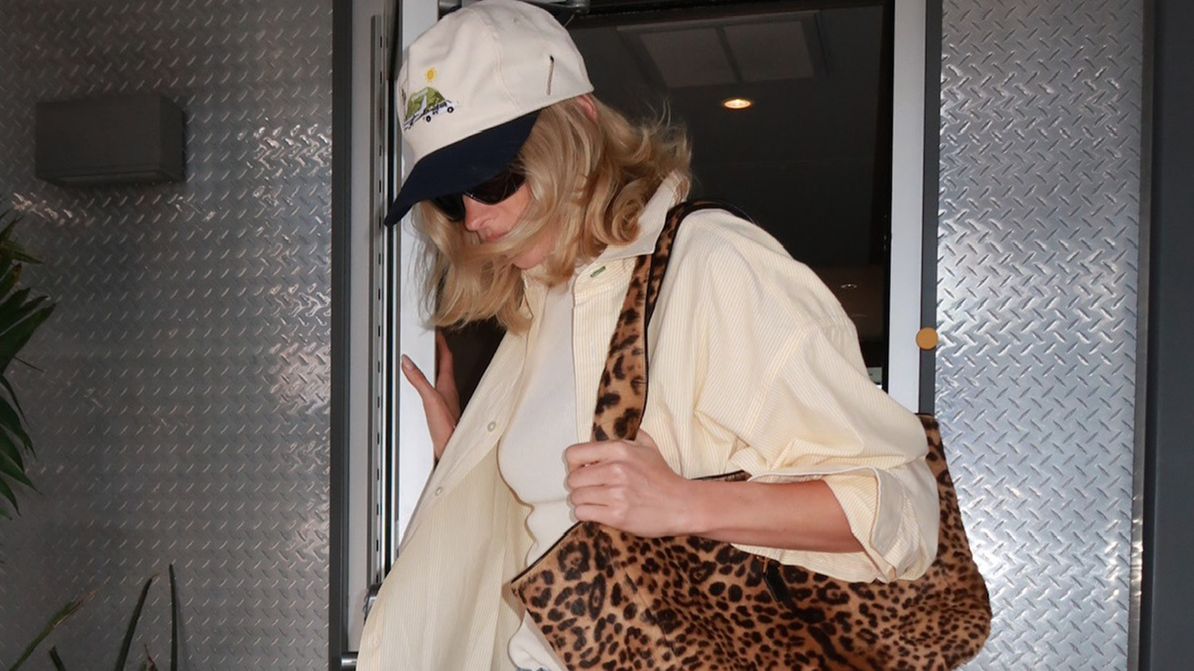 Photo of model Elsa Hosk wearing white tank, yellow button-down, and leopard print bag.