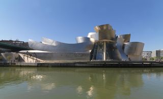 The Guggenheim Museum in Bilbao. A large silver structure in front of a river.
