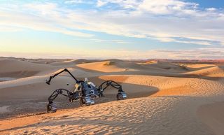 a robotic many-legged mechanobot traverses over hills of sand.
