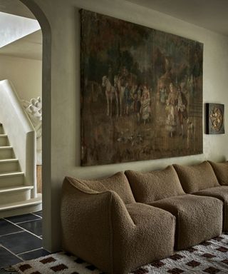 modern living room with limewash walls, a low boucle sofa, checkered rug and large vintage wall art