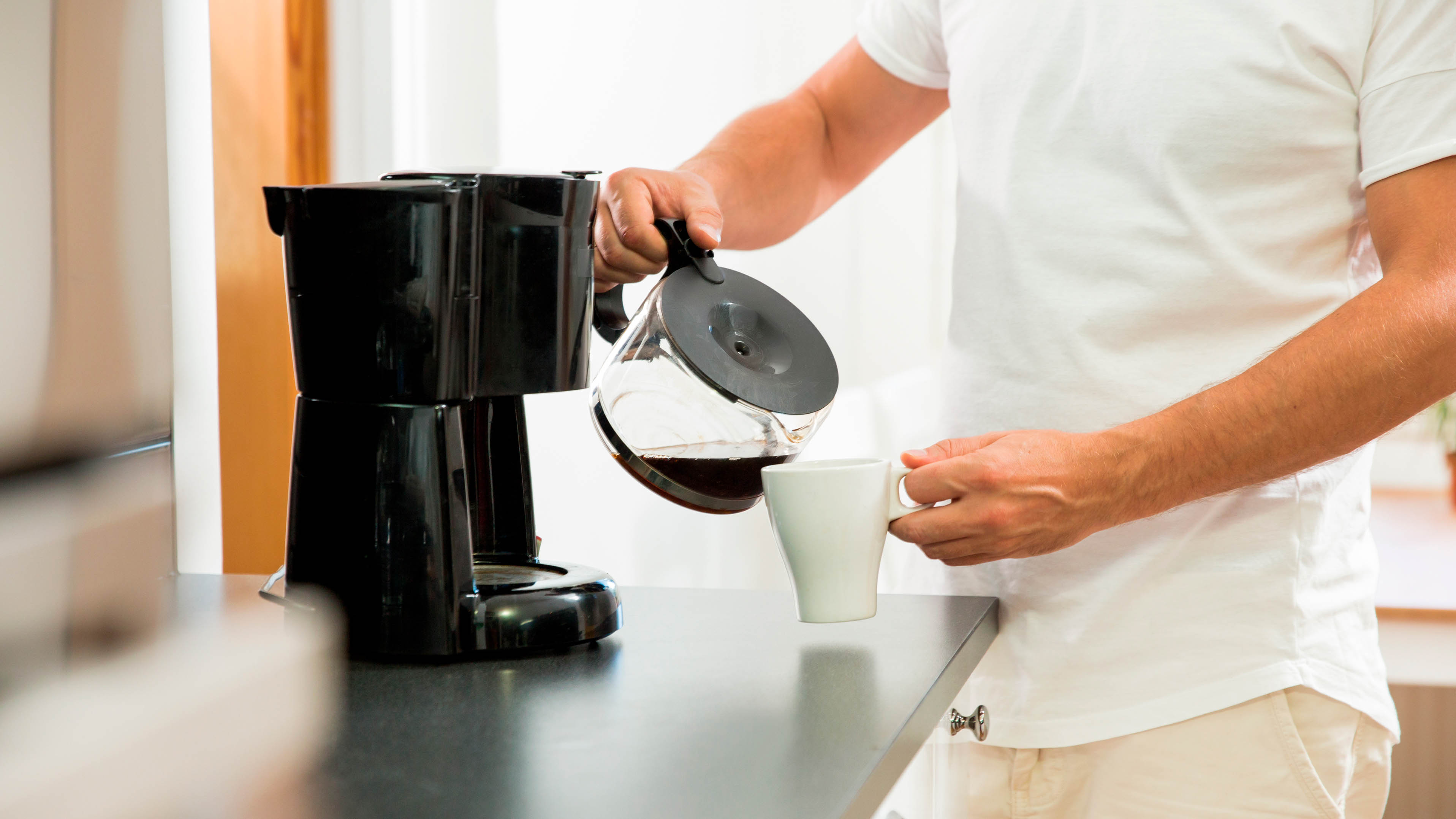 A coffee maker pouring fresh coffee into a cup