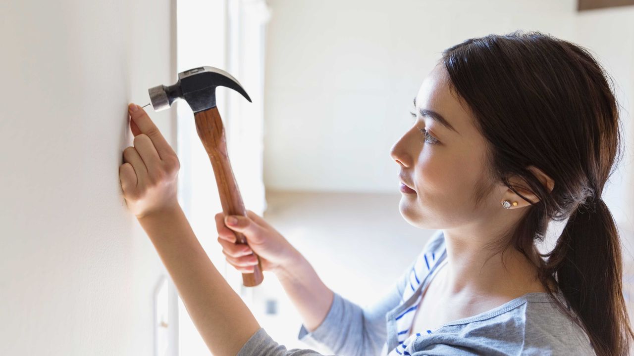 Woman hammering nail into wall