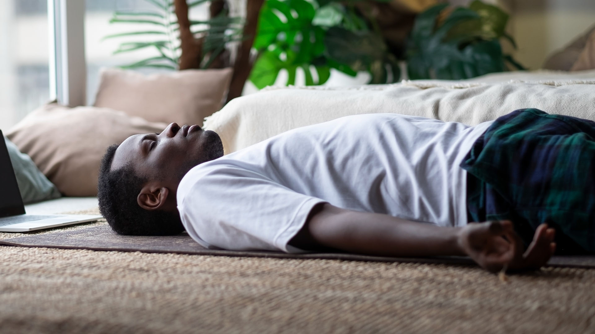 Мужчина лежит на спине на коврике для йоги с закрытыми глазами