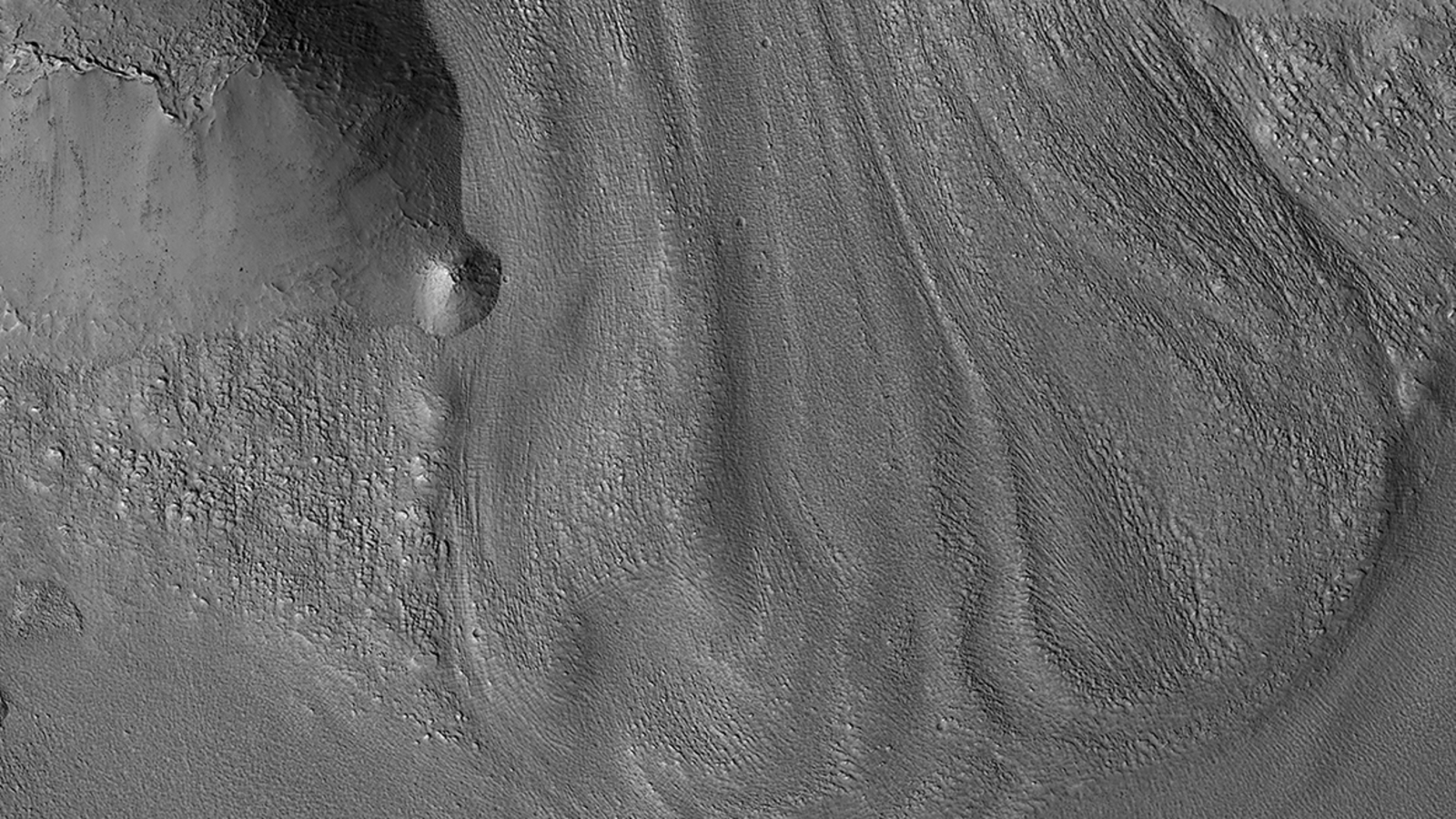 A gray-scale photo of a glacier on Mars, where debris covers any potential water ice below